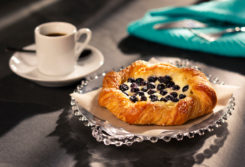Little Rae's Bakery Blueberry Cheese Croissant pictured alongside a cup of coffee.